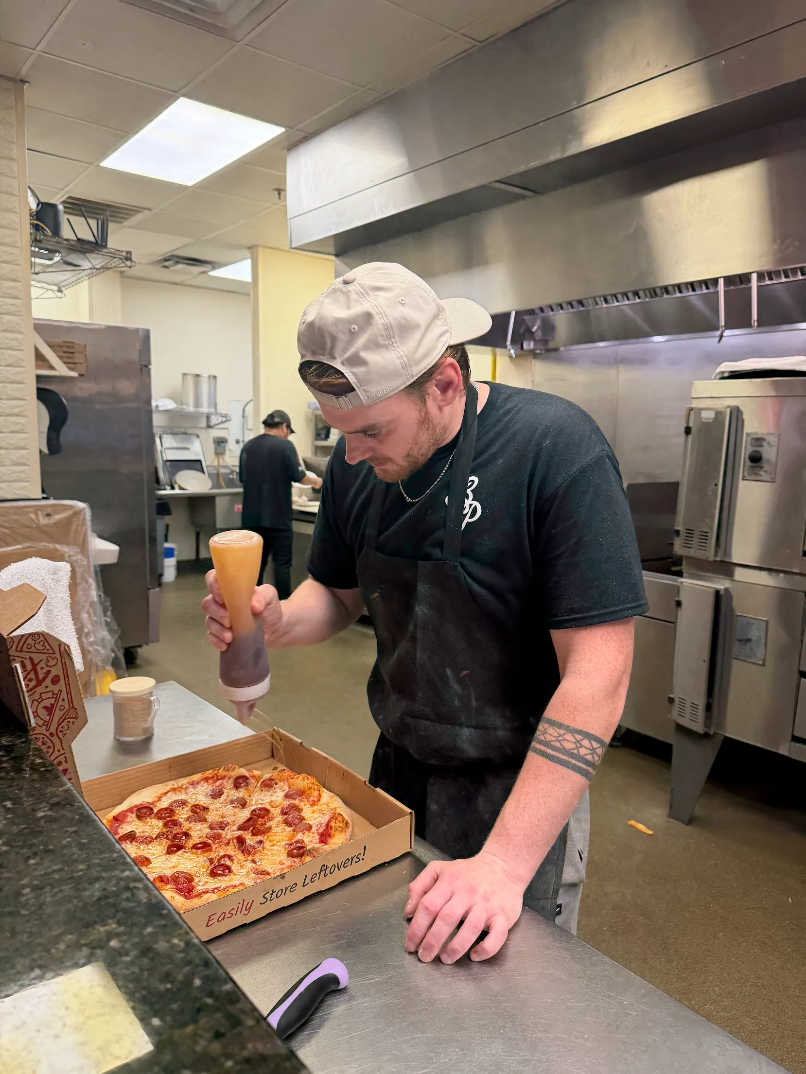 Alec drizzling Hot Honey on the Hot Honey Pizza at Bambino's Pizza, Morrisville, NC